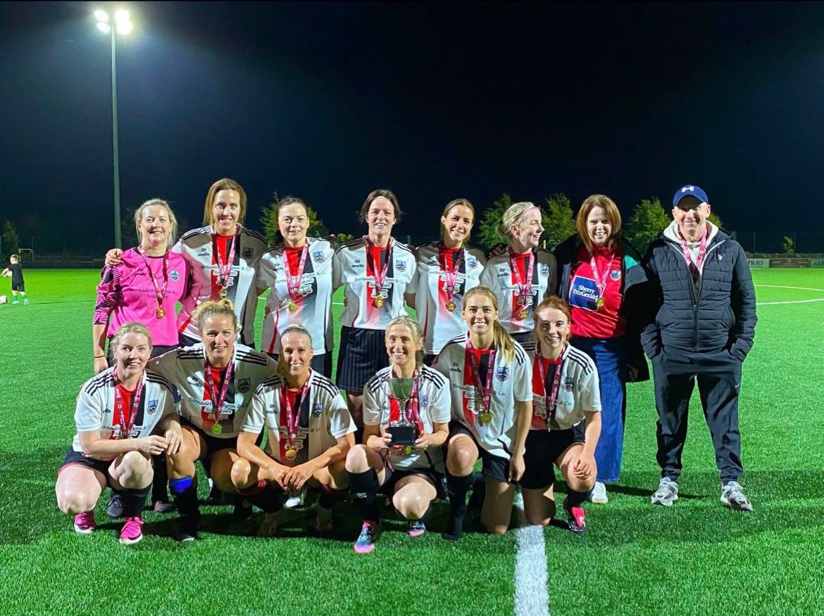 Cregmore Over 35s Ladies team celebrating under the floodlights with medals and their trophy